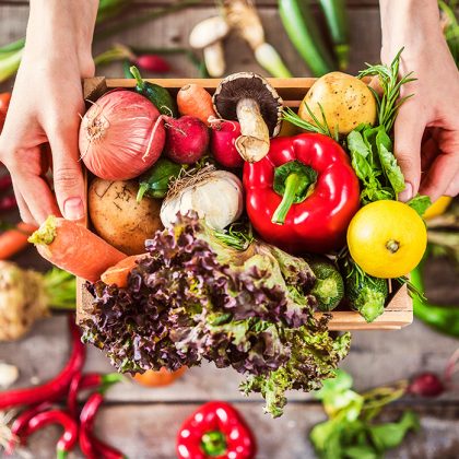 organic-food-in-box-held-over-wooden-background